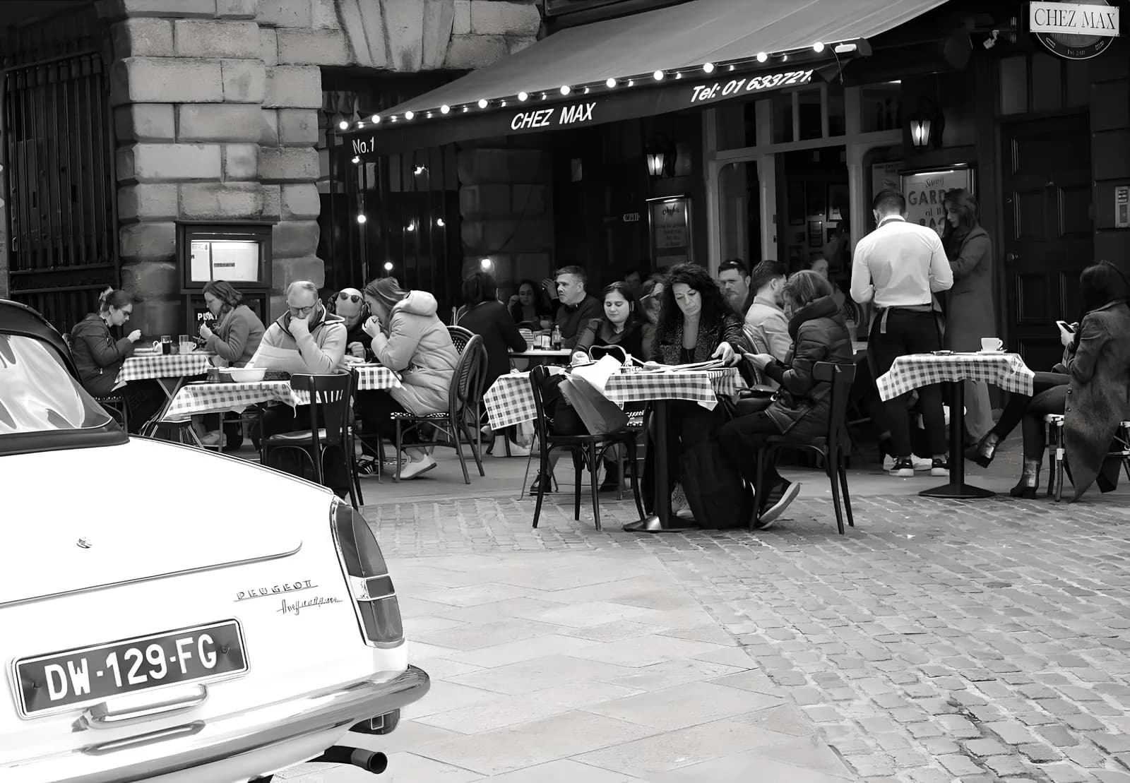 Black-and-white view of the Chez Max terrace on Palace Street, with the Peugeot 404 parked out front